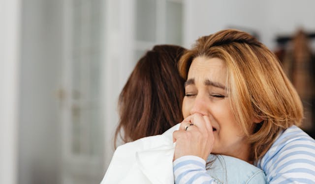 A comforting embrace between two women indoors, highlighting empathy and support.