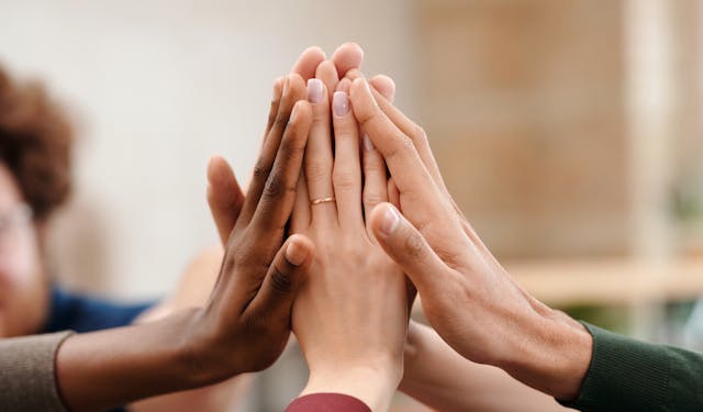 Close-up of diverse group hands high-fiving symbolizing teamwork and unity.