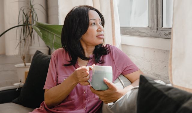 Woman enjoying a quiet moment with coffee, looking out the window.